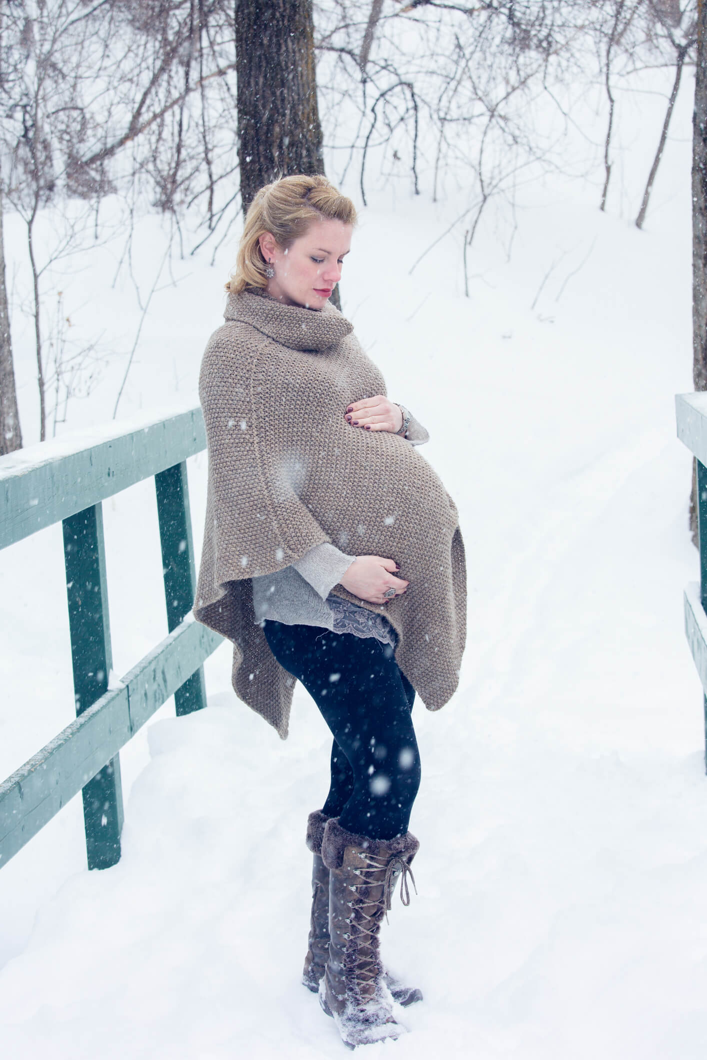 Pregnant lady standing in snow in woolly poncho