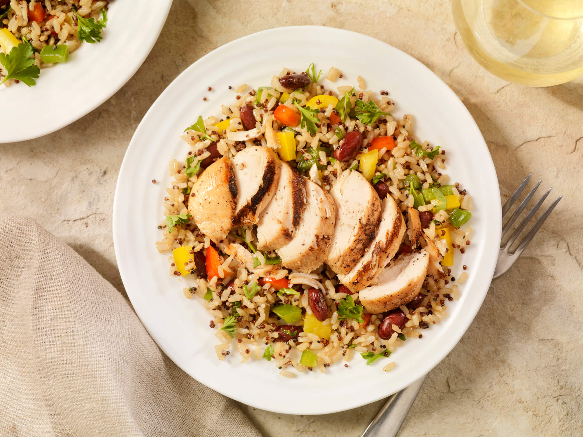 A grilled chicken with quinoa and brown rice dish in a white bowl