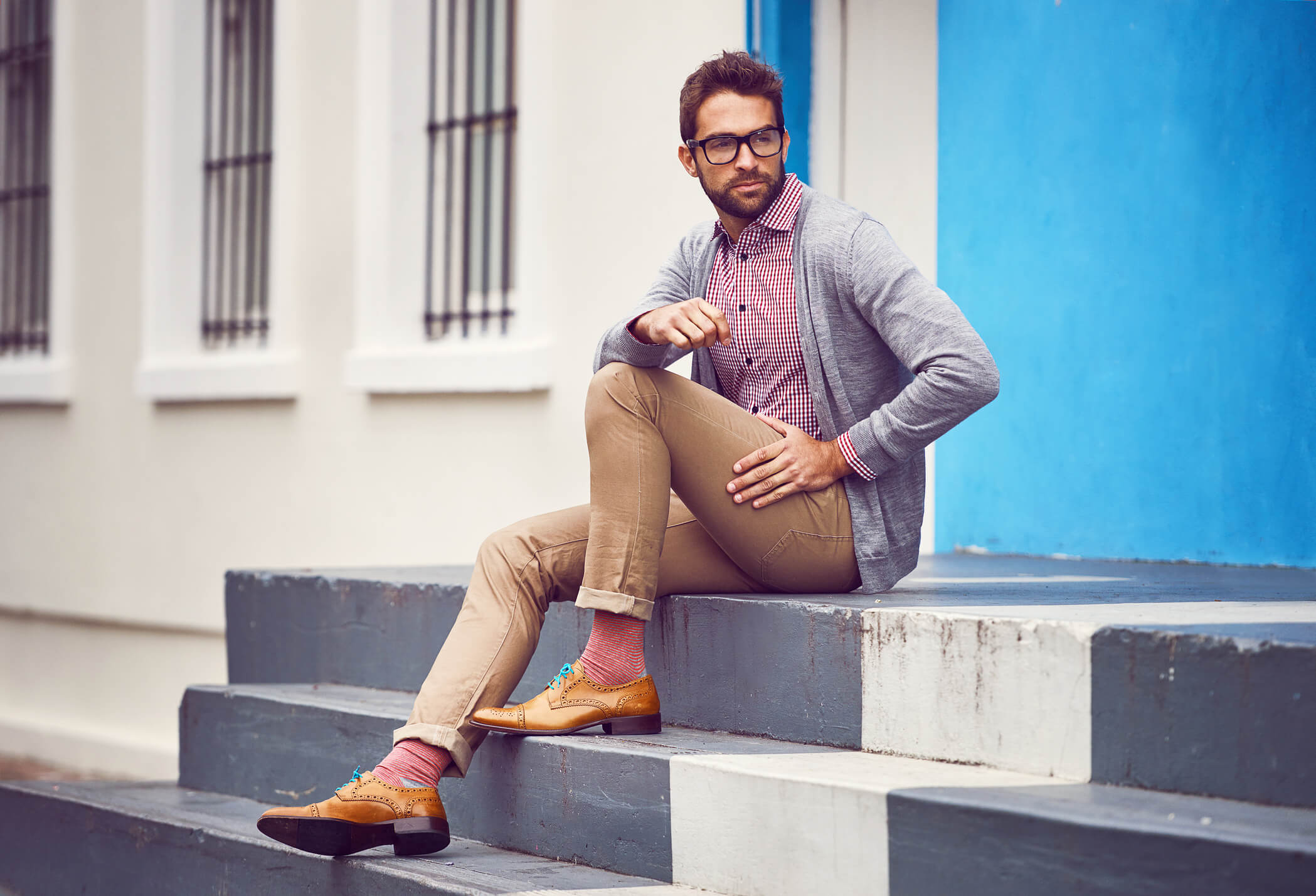 A man wearing neat casual clothing while sitting on concrete steps